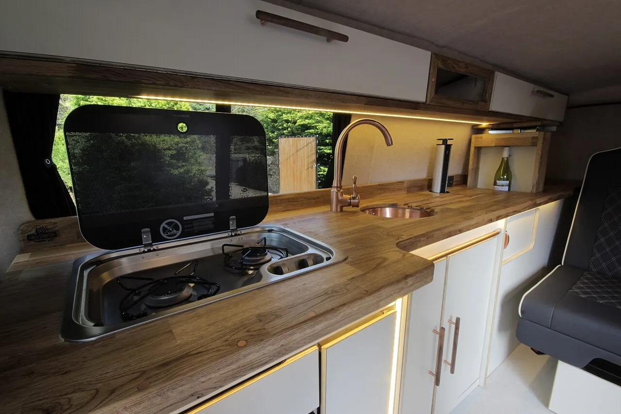 Intérieur d'un van aménagé moderne avec cuisine compacte et couchage transversal